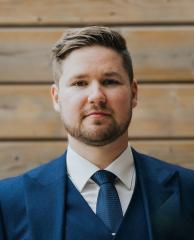 Sam Smagala stands in a blue suit.