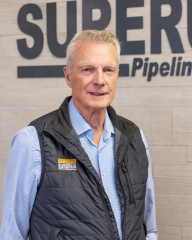 Brian poses in front of a Surerus logo.