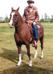 Ernie sits atop a brown horse as he poses for a photo.